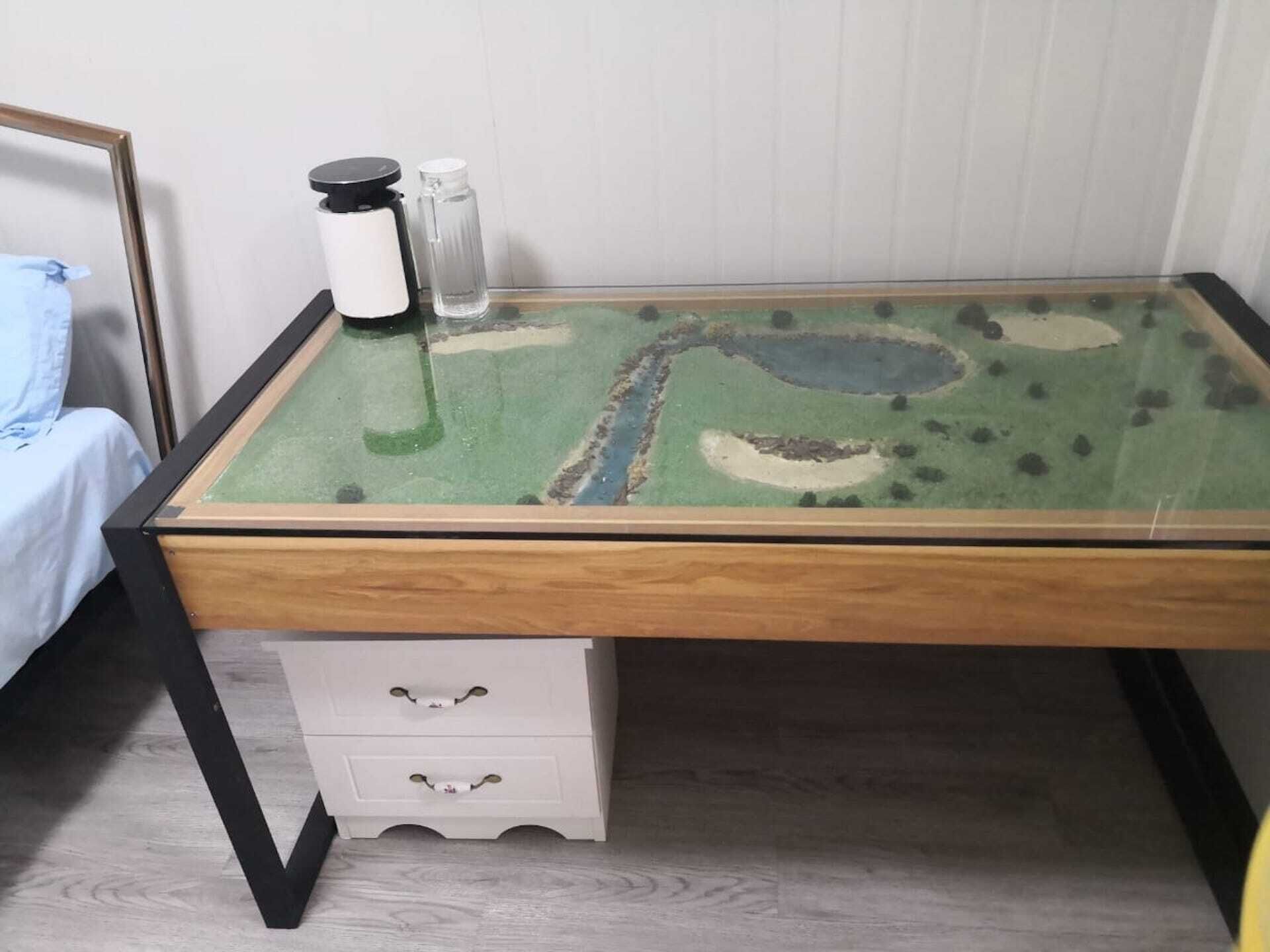A pool table with a green felt surface and a miniature golf course design.