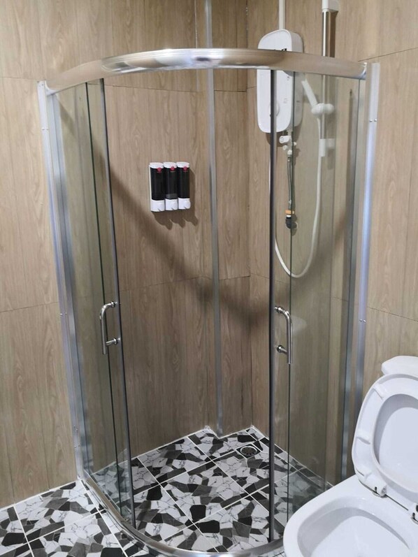 A shower enclosure with a glass door, a white toilet, and a patterned floor. - Titiwangsa Cabin Retreats by Vale Pine (Kuala Lumpur)
