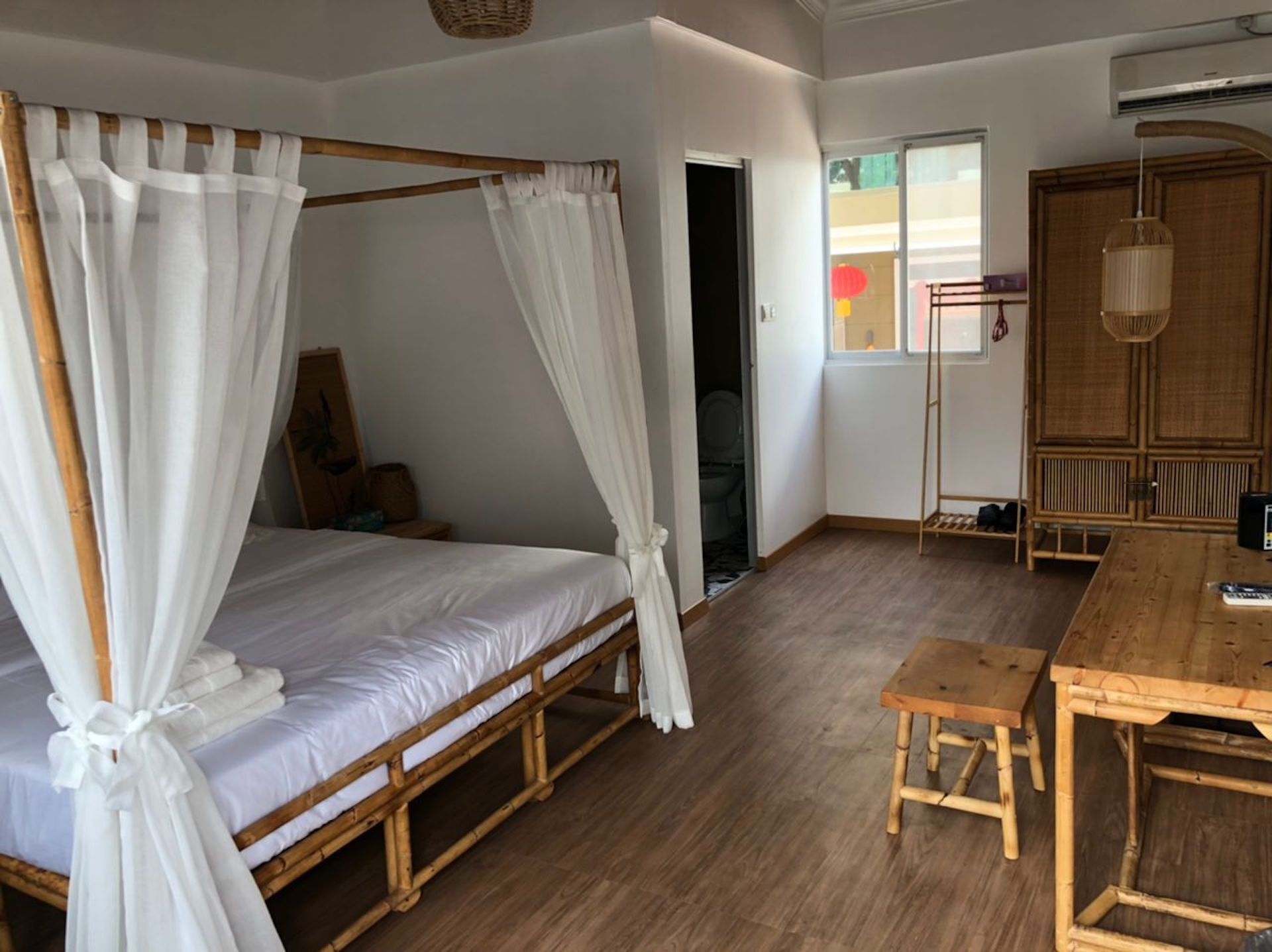 A room with a four-poster bed, a wooden table, and a chair.