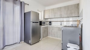Une cuisine moderne avec des meubles gris, un réfrigérateur en acier inoxydable, un four à micro-ondes et une cuisinière à gaz.