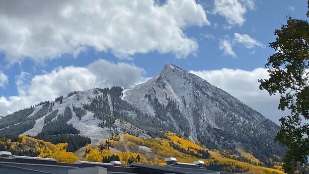 A mountain with a snow-capped peak, surrounded by autumn-colored trees and a clear sky. - Cozy 1 Bedroom, Sleeps 3, Steps from Shuttle! Hot Tub! Loved by guests! (Crested Butte)