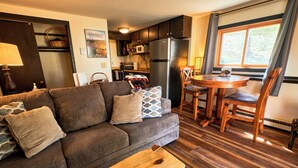 A living room with a sofa, coffee table, and dining area with chairs and a table. - Cozy 1 Bedroom, Sleeps 3, Steps from Shuttle! Hot Tub! Loved by guests! (Crested Butte)