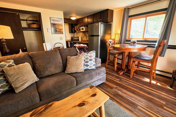 A living room with a sofa, coffee table, and dining area with chairs and a table. - Cozy 1 Bedroom, Sleeps 3, Steps from Shuttle! Hot Tub! Loved by guests! (Crested Butte)