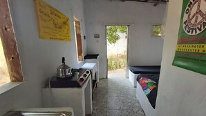 Un couloir étroit, carrelé, avec un lavabo, une petite table et un banc. Des panneaux sont accrochés aux murs et une affiche se trouve sur le côté droit.
