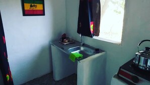 Une petite cuisine avec un évier, une fenêtre avec un rideau, une cuisinière et un drapeau accroché au mur.