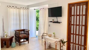 Ein geräumiger Wohnbereich mit einer Holzsofa, einem Esstisch und einem an der Wand befestigten Fernseher.