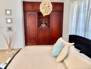 Ein Schlafzimmer mit einem großen Bett, einem Holzschrank und einer Pendelleuchte.