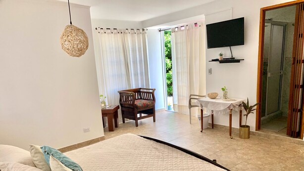 Ein Schlafzimmer mit einem Bett, einem Schreibtisch, einem Sessel und einem Fernseher.