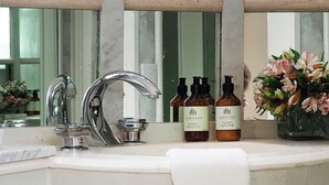 Ein Badezimmer mit einem weißen Waschbecken, einem Spiegel und zwei Flaschen Loredana Duschgel.