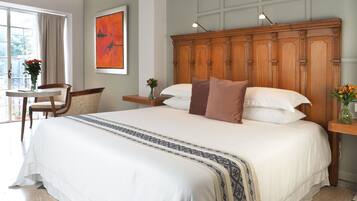 A neatly made bed with a patterned bedspread, a wooden headboard, and a bedside table with a vase of flowers.
