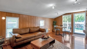 A modern living room with a brown leather sofa, wooden coffee table, and a dining area with a table and chairs. - King Estate with attached Mid-Century Apartment & Gym. (Wichita)