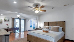 A spacious bedroom with a wooden bed, a desk, and a ceiling fan. - King Estate with attached Mid-Century Apartment & Gym. (Wichita)