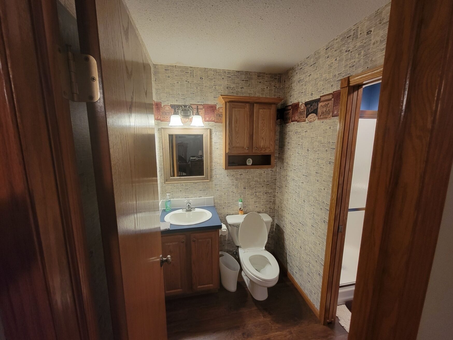 A compact bathroom with a sink, toilet, and wooden cabinets.