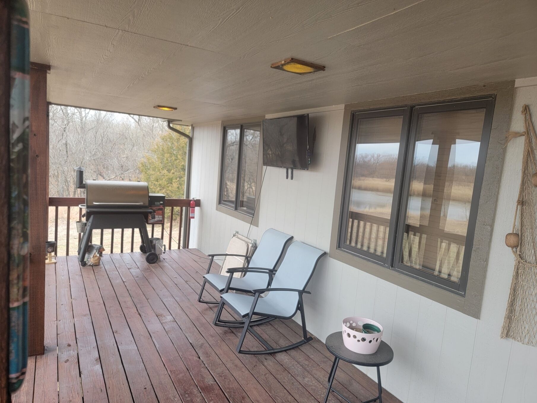 A covered porch with a grill, two rocking chairs, and a small table with a basket.