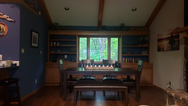 A dining area with a wooden table and chairs, surrounded by shelves with various items. - 2-bedroom vacation home sitting on your own private lake for fishing/relaxing. (Howard)