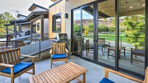 Une terrasse dotée de mobilier en bois, d’un barbecue et offrant une vue sur un terrain de golf.