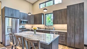 Une cuisine moderne avec des meubles en bois foncé, des appareils électroménagers en acier inoxydable et un îlot central en granit.