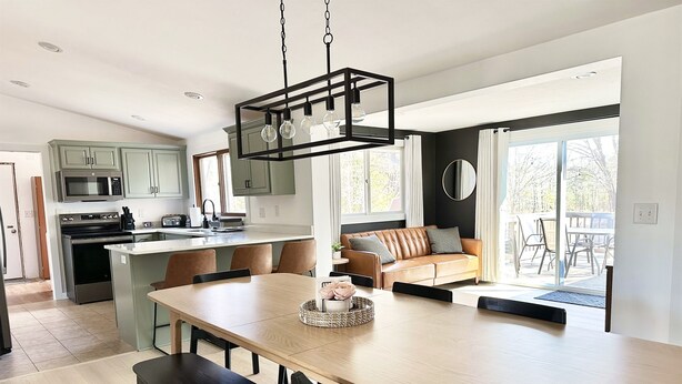 A modern kitchen with a central island, a dining area with a bench, and a view of the outdoors. - Orchard Ranch - Fish Creek | Sleeps 10 • Trails • Coffee Bar • Snowshoes (Fish Creek)