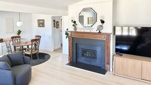 A modern living room with a fireplace, a dining area, and a TV. - Orchard Ranch - Fish Creek | Sleeps 10 • Trails • Coffee Bar • Snowshoes (Fish Creek)