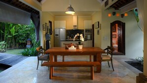 A spacious kitchen with modern appliances, a dining area with a wooden table and benches, and a view of lush greenery outside. - Spacious, 800sqm, Pool and Garden Retreat, Sanur Village (Sanur)