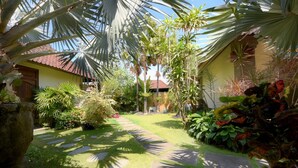A tropical garden with a stone pathway leading to a building with a red-tiled roof. - Spacious, 800sqm, Pool and Garden Retreat, Sanur Village (Sanur)