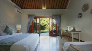 A hotel room with two beds, a desk, and a view of a pool and garden. - Spacious, 800sqm, Pool and Garden Retreat, Sanur Village (Sanur)