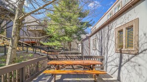Une terrasse en bois avec une table de pique-nique, entourée d’une clôture en bois et d’arbres.
