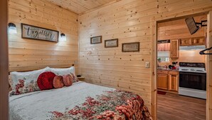 A cozy wooden cabin interior with a bed, a kitchen, and a dining area. - Cuddling On The Creek Couples only romantic " TINY CABIN" retreat!!!! (Cosby)