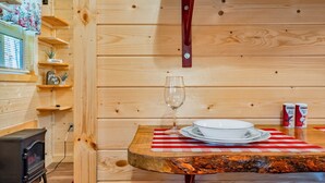A wooden interior with a dining table, a wine glass, and a plate set. - Cuddling On The Creek Couples only romantic " TINY CABIN" retreat!!!! (Cosby)