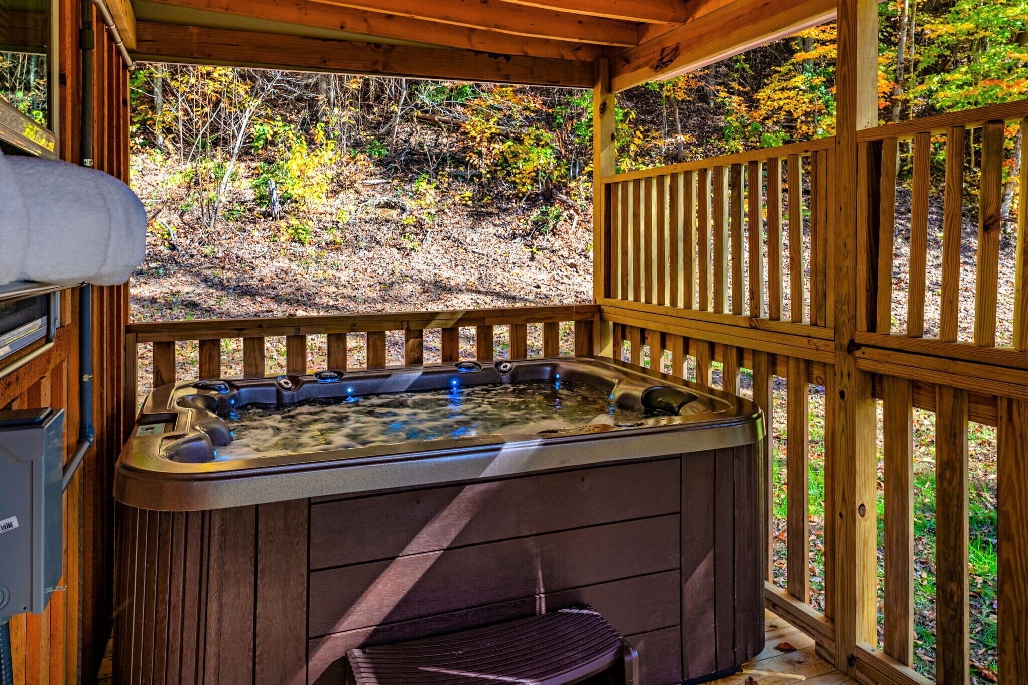 Un jacuzzi en una terraza de madera con vistas a un bosque.