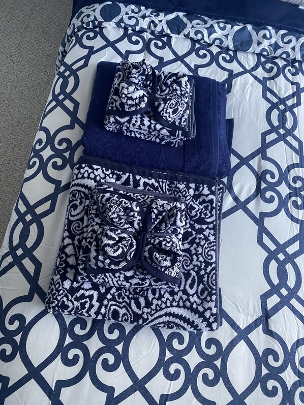 A neatly arranged bed with a patterned blue and white duvet cover and matching pillows.