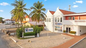 Un bâtiment avec une enseigne indiquant « Vacation Aruba.com » et des palmiers au premier plan.