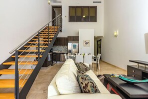 Una sala de estar moderna con una escalera, un comedor y una cocina.