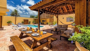 Une terrasse extérieure avec une piscine, des meubles en bois et des plantes en pot.