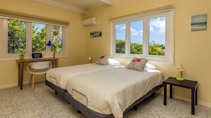 Une chambre avec un grand lit, deux fenêtres, un bureau et une chaise.