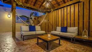 Un espace extérieur aménagé avec deux canapés et une table, des murs en bois et un toit de chaume.