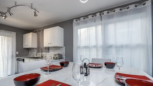 A modern dining area with a marble table, red and black bowls, and wine glasses.