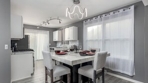 A modern kitchen with a central island, white cabinets, and a dining area with a table set for four.