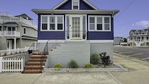 A two-story house with a front porch, a staircase, and a small garden area.