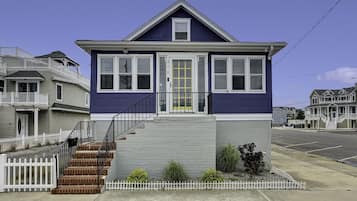 A two-story house with a front porch, a staircase, and a small garden area.