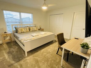Um quarto com uma cama, mesas de cabeceira, uma escrivaninha e uma cadeira.
