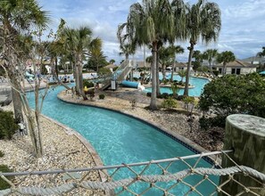 Zona de piscina con varias piscinas, palmeras y un parque infantil.