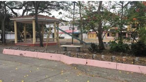 Un kiosque avec un toit rouge, un banc et une aire de jeux avec un toboggan.