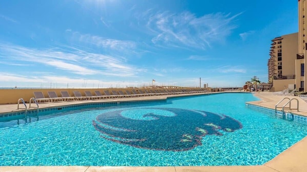 A swimming pool with a spiral design, sun loungers, and a tall building in the background.
