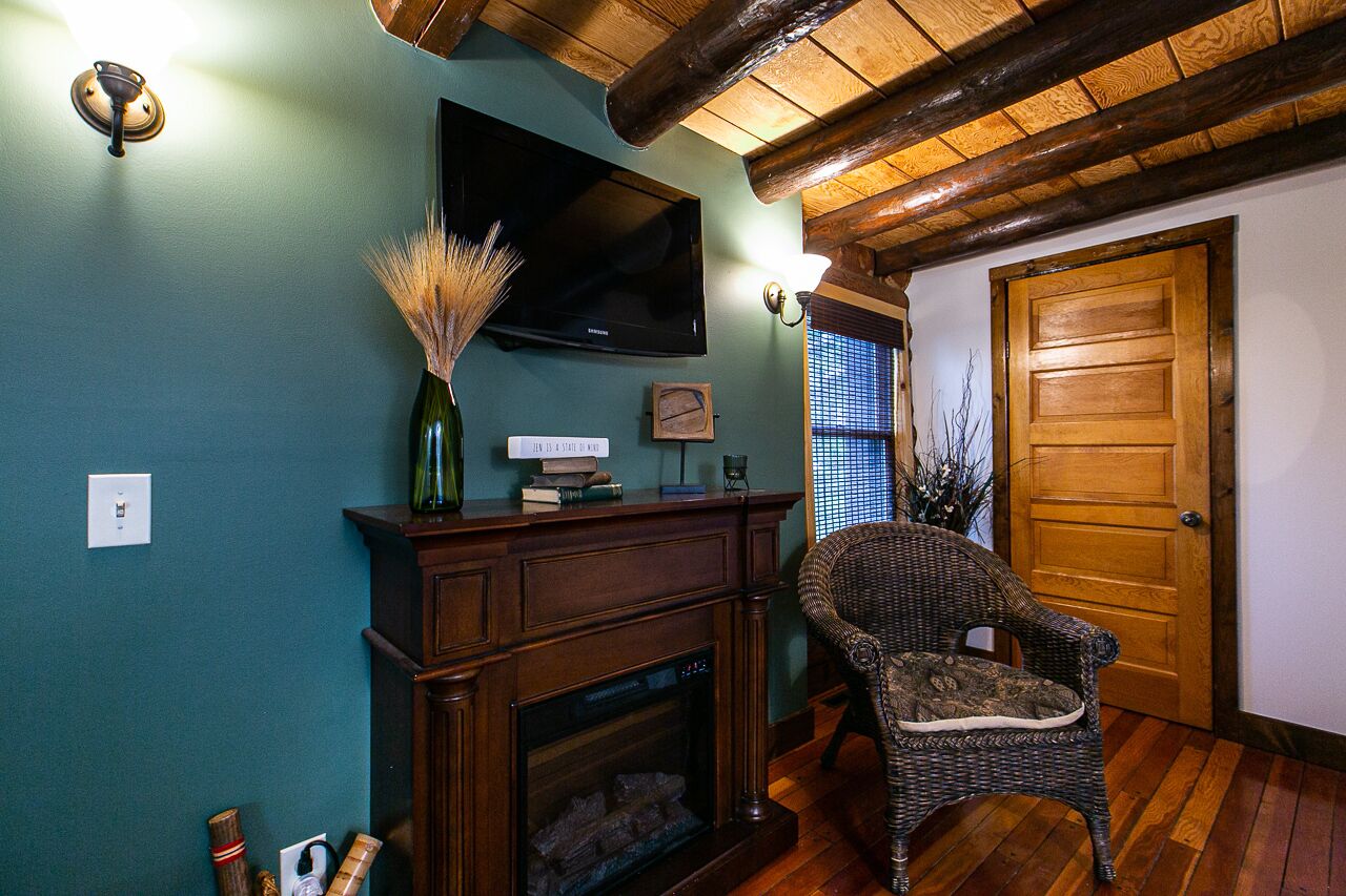 A cozy room with a fireplace, a television mounted on the wall, and a wooden door.