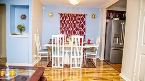 A dining area with a table and chairs, a chandelier, and a kitchen with a refrigerator. - Luxe 7 bdr 4 Fullbath with Jacuzzi on West side Detroit (Detroit)