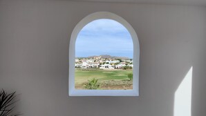 A room with a large arched window overlooking a residential area with houses and a hill. - Luxury Golf View 3Bed Penthouse, Sleeps 6, Balcony (Mar Menor Golf)