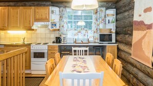 A cozy cabin-style kitchen with wooden cabinets, a dining table, and a large window.