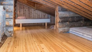A log cabin room with a wooden floor, a bed, and a mattress on the floor.