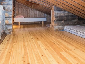 A log cabin interior with a wooden floor, a bed, and a stone wall.